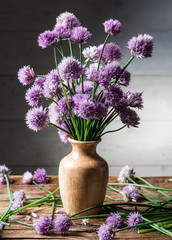 Bouquet of onion (chives) flowers in the vase on the wooden tabl