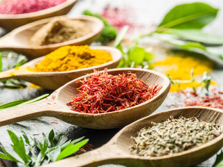 Assortment of colorful spices in the wooden spoons.