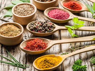 Assortment of colorful spices in the wooden spoons.