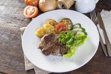 grilled pork steak with vegetable on a white plate