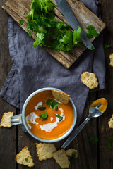 Carrot soup in a cup with cream and herbs