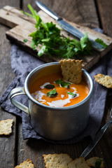 Carrot soup in a cup with cream and herbs