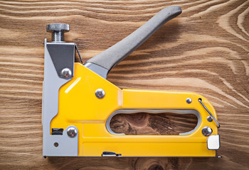 Stapler gun on wooden board top view construction concept