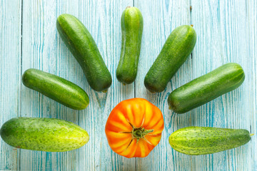 ripe raw tomatoes and some raw ripe cucumbers on wooden backgrou