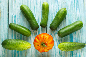 ripe raw tomatoes and some raw ripe cucumbers on wooden backgrou