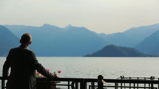 Silhouette of handsome groom watching the mountains and lake view in Como, Italy. Back view
