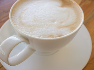 Selective focus blur a cup of Coffee latte on the wooden table