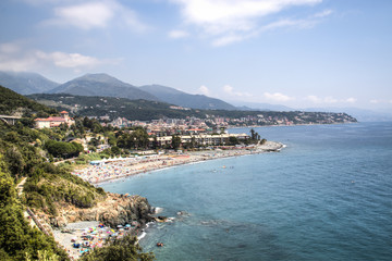 View over the coast and a village in the Liguria area in Italy with mountains in the back
