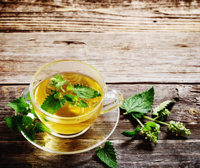 green melissa herbal tea in glass cup on wooden background
