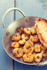 fried shrimps with bread on dish on blue wooden background