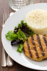grilled hamburger with rice, salad and chips on white plate