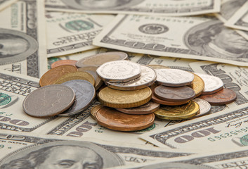 heap of coins on one hundred dollars banknotes