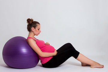 pregnant woman practicing yoga on a light background