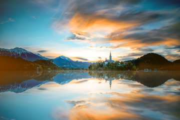 Beautiful morning landscape with snowed up Alpes on the Bled lake in Slovenia. Long exposure image technic with blurred clouds and glossy water