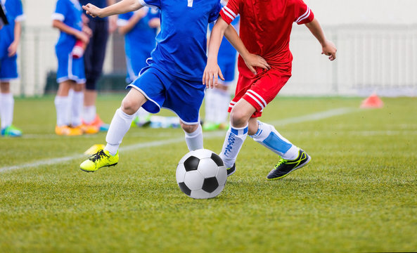 Young soccer players kicking football ball.
