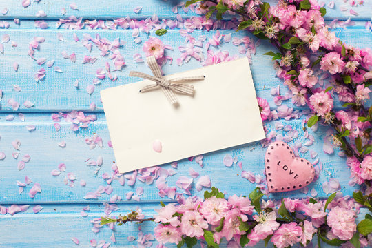 Pink  sakura flowers, empty tag and  heart on blue wooden planks