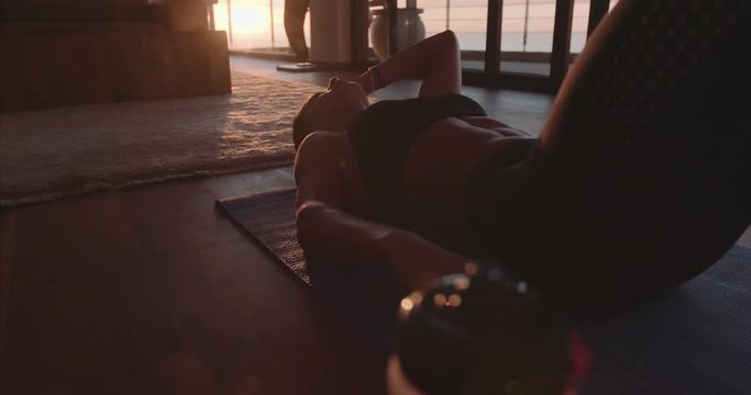 Fitness woman lying on exercise mat in living room of her apartment. Female relaxing on floor after workout and taking deep breath.
