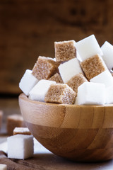 Cubes of white and brown sugar, wooden bowl, selective focus