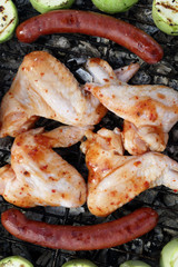Chicken wings with sausages on grill