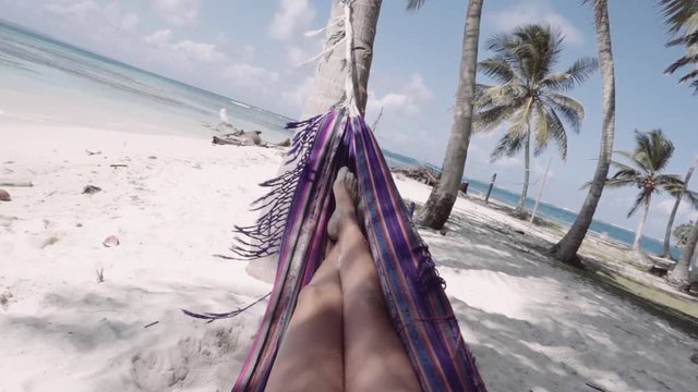 Hispanic woman relaxing in hammock on caribbean beach at San Blas islands, Panama