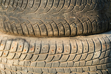 A stack of old tires with textured tread on sunlight closeup.