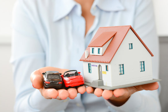 Businesswoman holding a house property and cars in palms