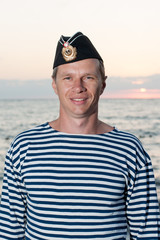 man standing in garrison cap and striped vest on the background