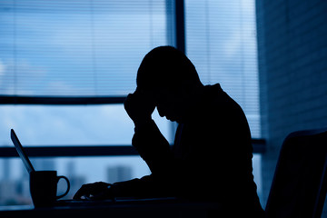 Stressed unhappy businessman working in dark office