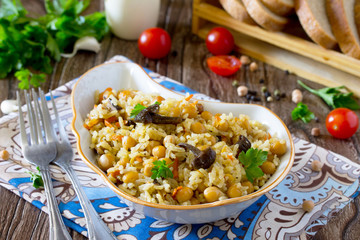 Vegetarian vegetable pilaf chickpea and wild mushrooms on a wood