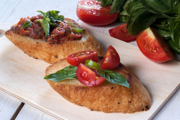 Snack in the Italian style: bruschetta with tomato and basil. At the rustic wooden table. 