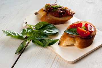 Snack in the Italian style: bruschetta with tomato and basil. At the rustic wooden table. 