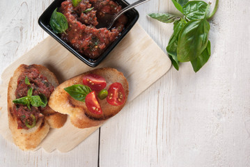 Snack in the Italian style: bruschetta with tomato and basil. At the rustic wooden table. 