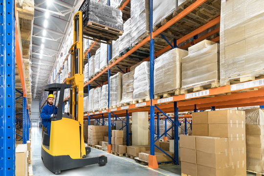 Young forklift driver in big distribution warehouse