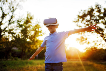 Fascinated little boy using VR virtual reality goggles. outdoor