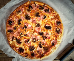 Delicious fresh pizza with mushrooms and bacon on a wooden background