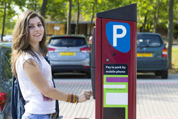 Young woman paying for parking outdoors