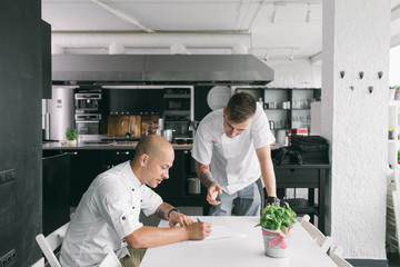 Chef writing on paper with student standing at table