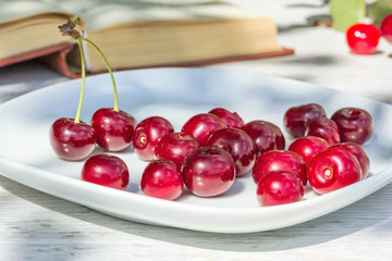 Cherries on a white plate and the book