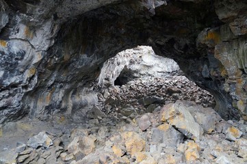 Former lava tube formed by hot, fluid magma. Over time the roof collapsed allowing light into the tunnel and rocks were deposited on the floor. Indian Tunnel, Craters of the Moon National Park.