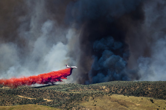 White Aircraft Dropping Fire Retardant as it Battles the Raging Wildfire