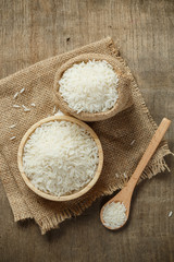 Jasmine rice in bowl and sack on wooden table