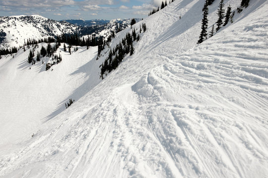 Steep run in an alpine ski area with tracks in the snow
