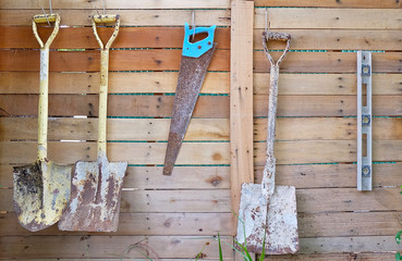 Agriculture and farming working tools hanging on vintage wooden wall.