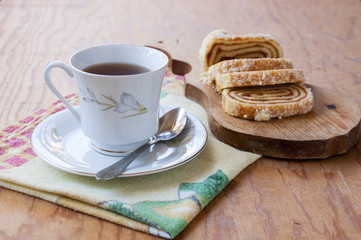 A cup and saucer with tea and delicious strudel