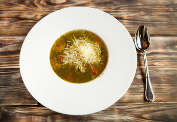 plate with vegetable soup it is decorated with grated cheese