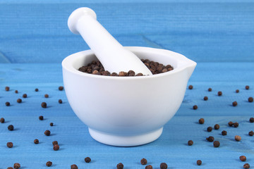 Black pepper in white mortar on blue boards