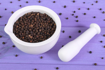 Black pepper in white mortar on purple boards