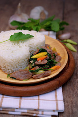 Stir fried spicy basil leaf with pork and rice on wooden table, Thai food.