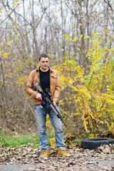 Fototapeta premium pensive man with an automatic weapon in the woods