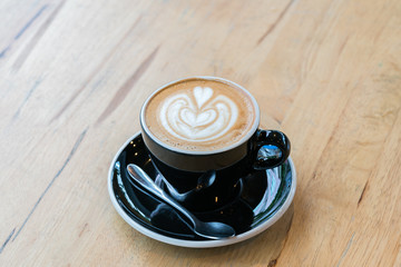 Cup of hot latte art coffee on wooden table

